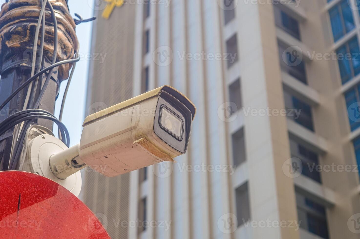 A CCTV surveillance camera attached to an electricity pole is monitoring the city photo