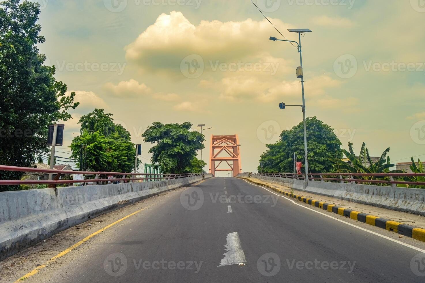 a lonely concrete arch bridge with no vehicles photographed from the middle of the highway photo