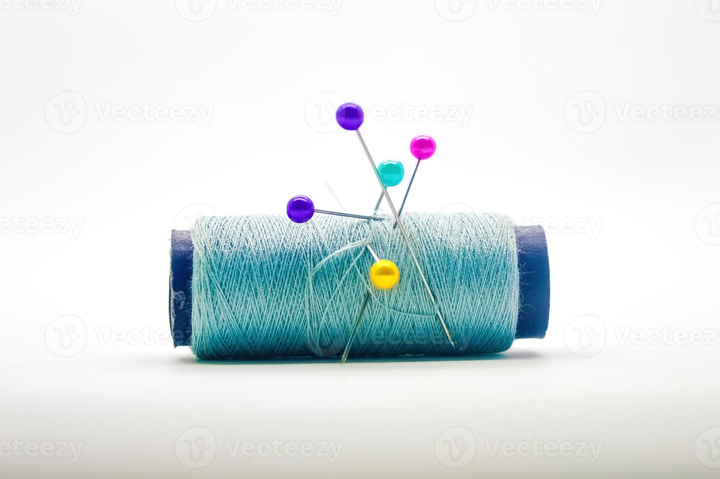 a roll of sewing thread pierced by a pin isolated on white background with copy space photo