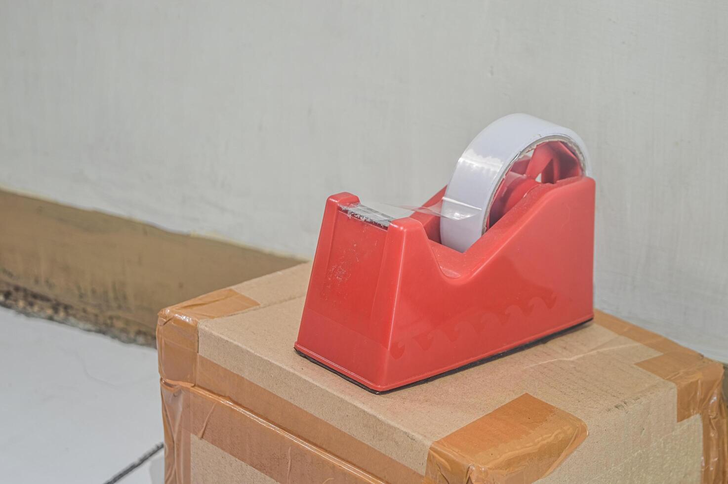 cardboard box insulated with tape for sending packages with a red tape dispenser on top photo