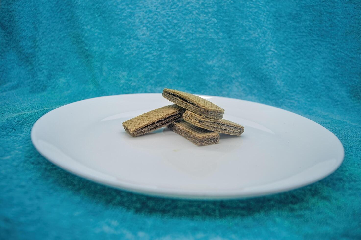 several wafers or wafers arranged on a plain white plate on a turquoise background photo