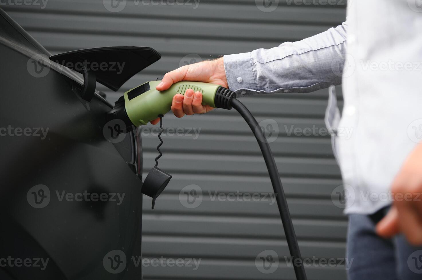 a man charges an electric car photo