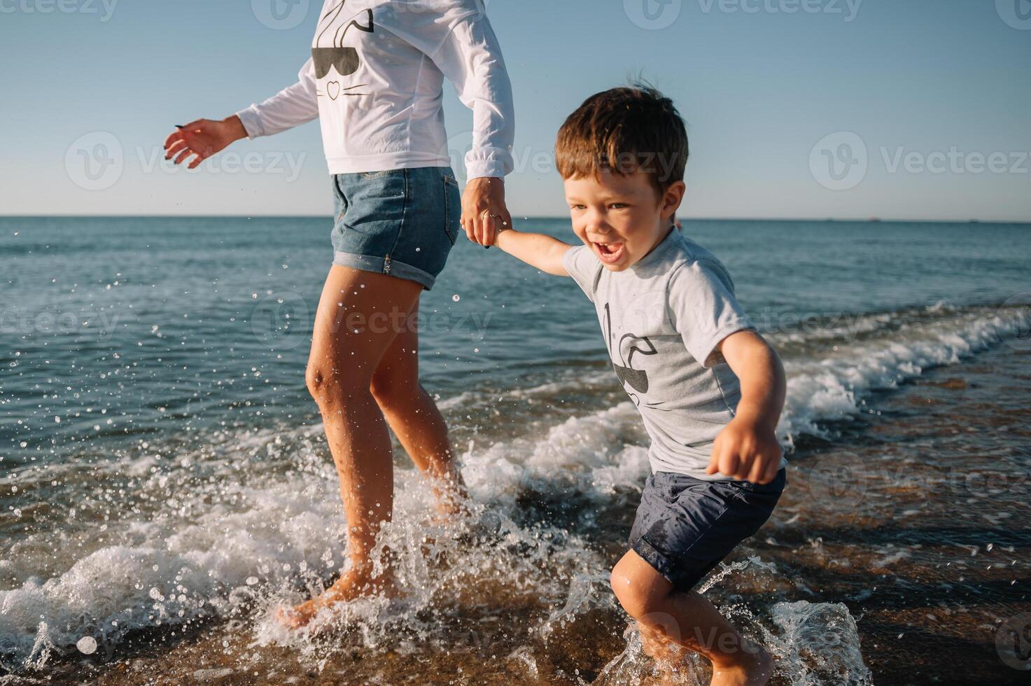 Mother and son playing on the beach at the sunset time. Concept of friendly family. photo