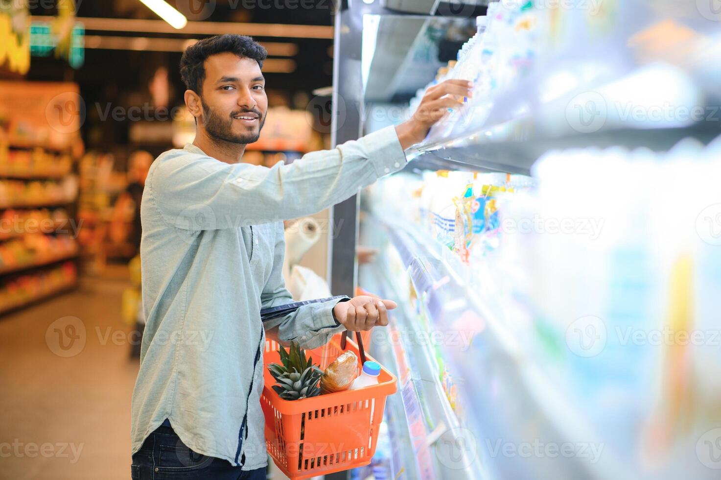 Portrait of handsome young Indian man standing at grocery shop or supermarket, Closeup. Selective Focus. photo