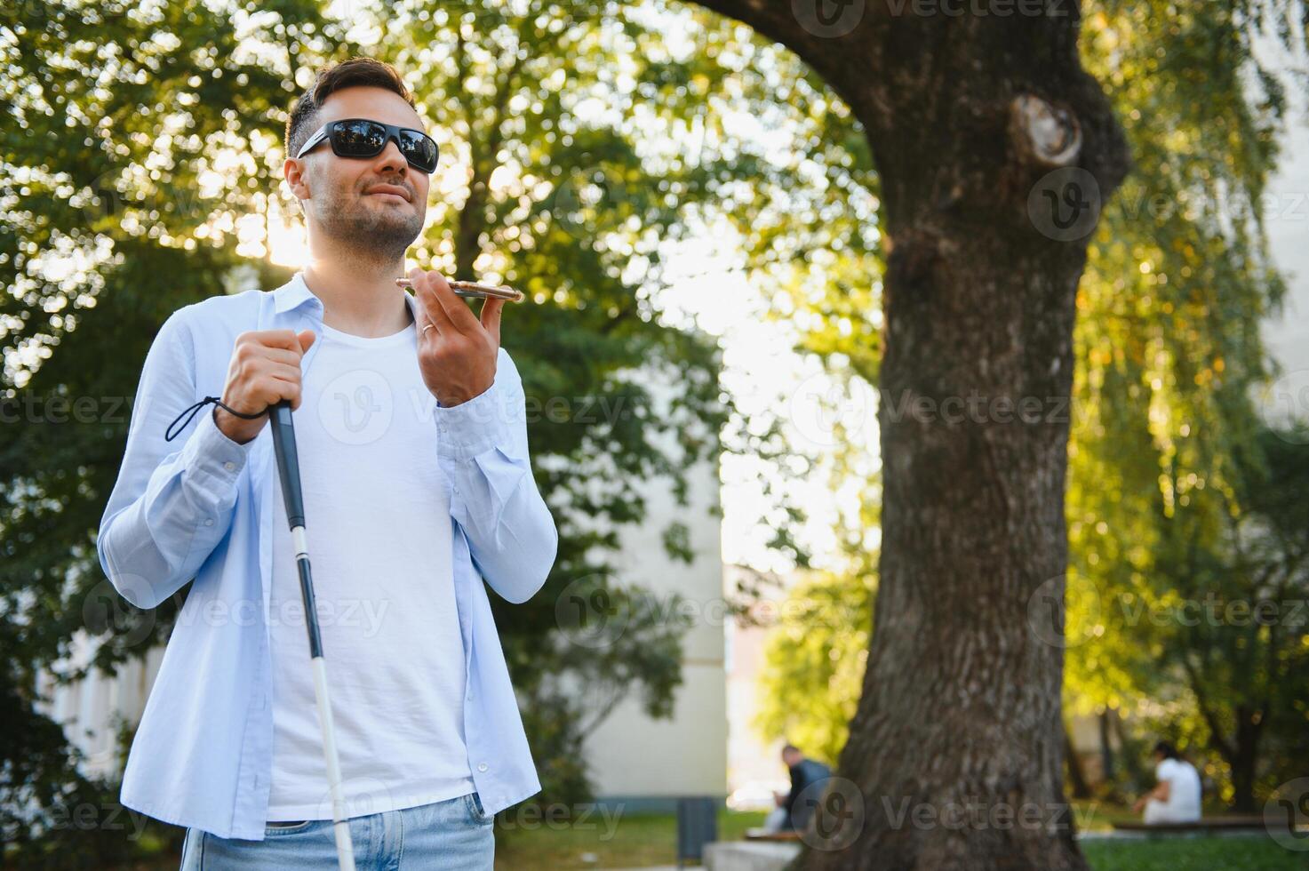 Young blinded man using phone and sending voice message photo