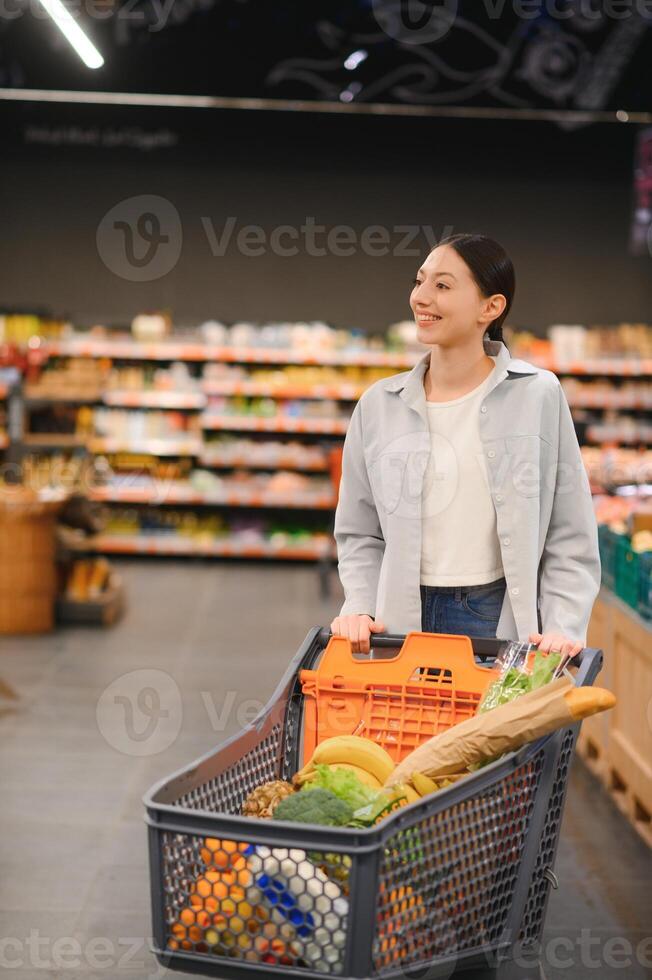 Happy young woman looking at product at grocery store. Smiling woman shopping in supermarket photo