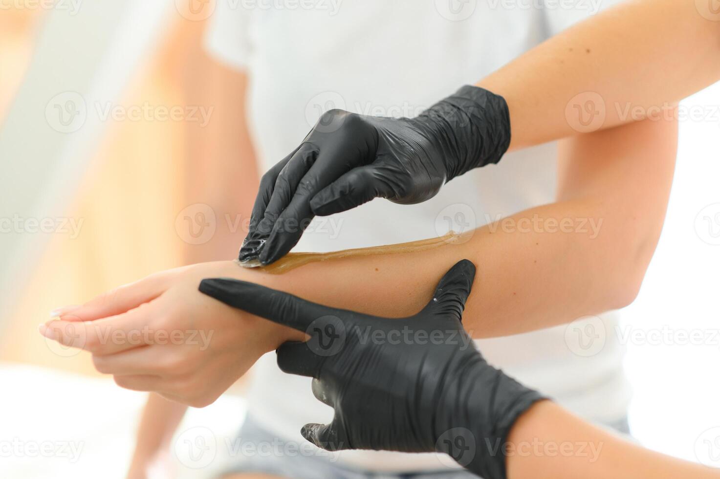 A beautician makes a sugar paste depilation of a woman's hand in a beauty salon photo