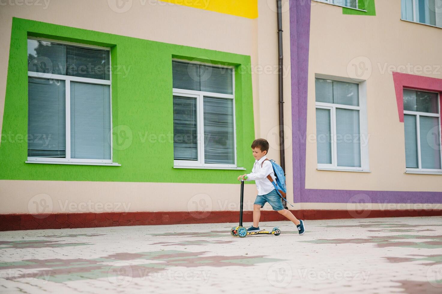 Boy goes to school on a scooter. Children back to school scoote.Childschool riding a scooter. Back to school. Happy children. Happy childhood lifestyle. Student goes to school photo