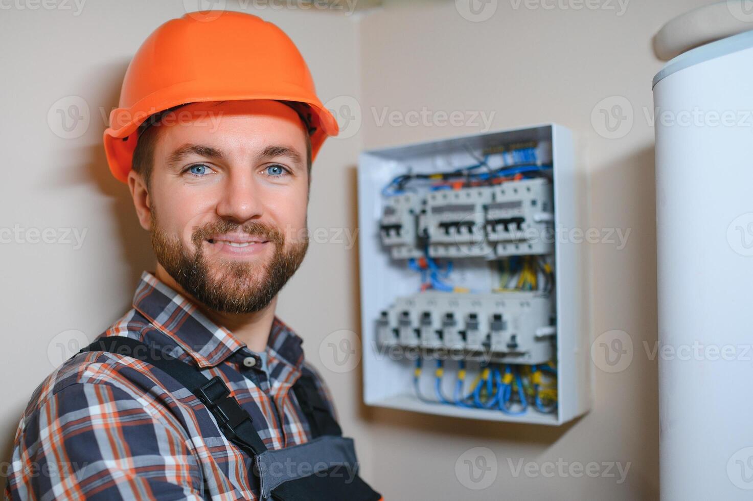handsome young man electrician working on switchboard of house building construction site photo