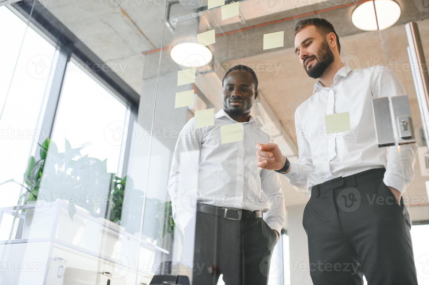 colleagues discuss and stick notes on the glass photo