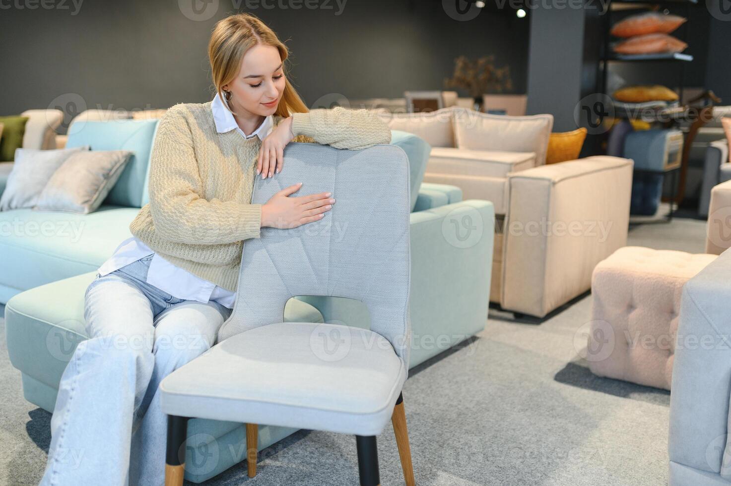 A young woman chooses chairs for the home in a store. photo