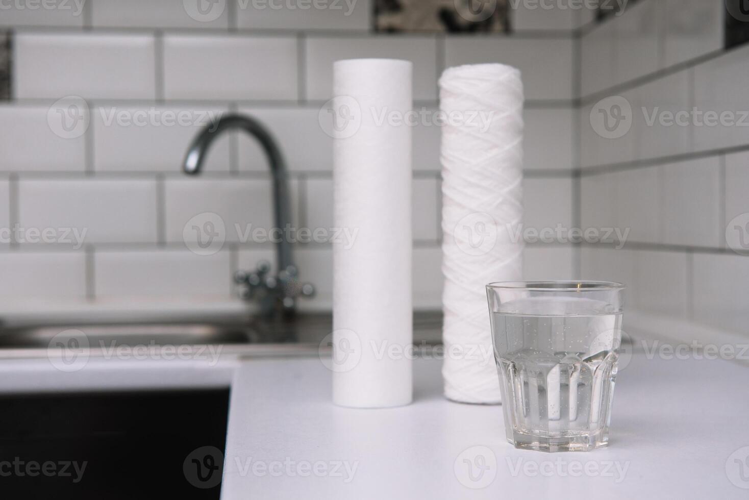 Water filters. Carbon cartridges and a glass on a white kitchen background. Household filtration system photo