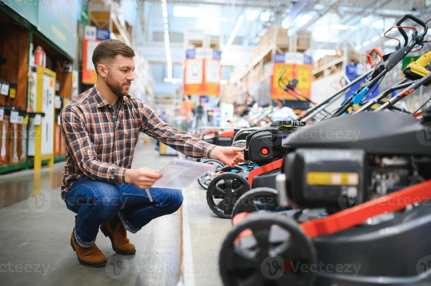 a customer in a hardware store chooses a gas or electric lawn mower photo