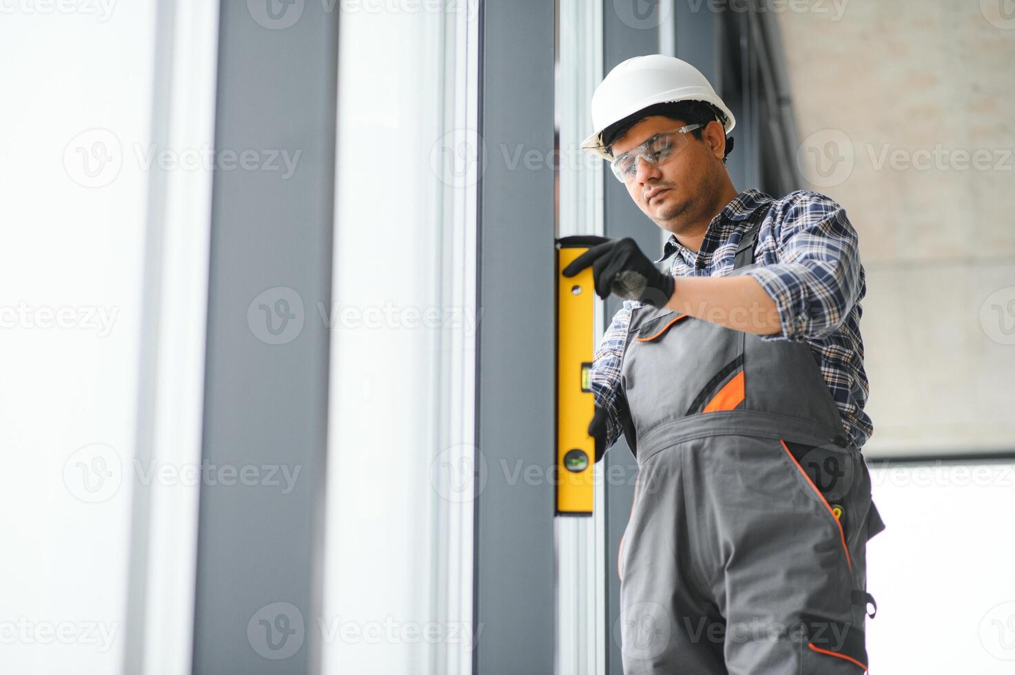 Workman in overalls installing or adjusting plastic windows photo
