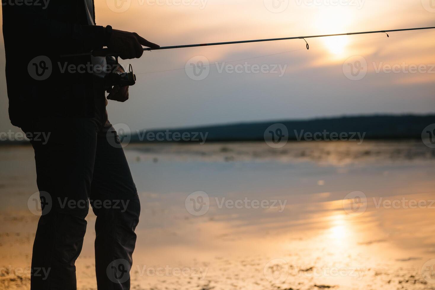 The fisherman's hands, holds the spinning rod, rotates the coil handle. Hobby and activity. photo