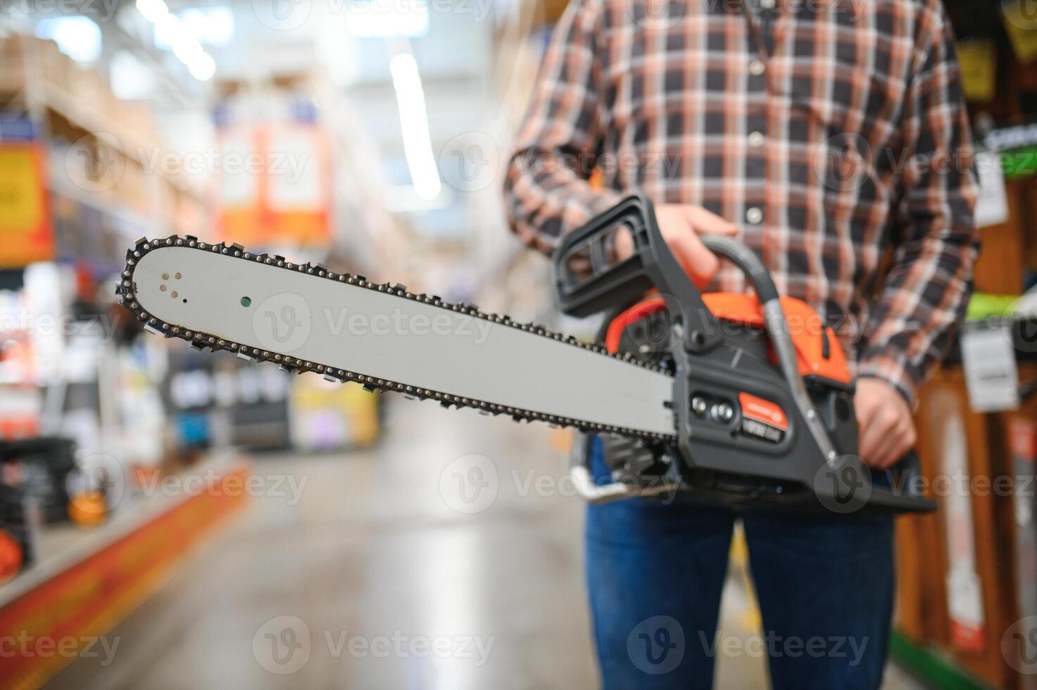 young male is standing with new electric saw in tools store photo