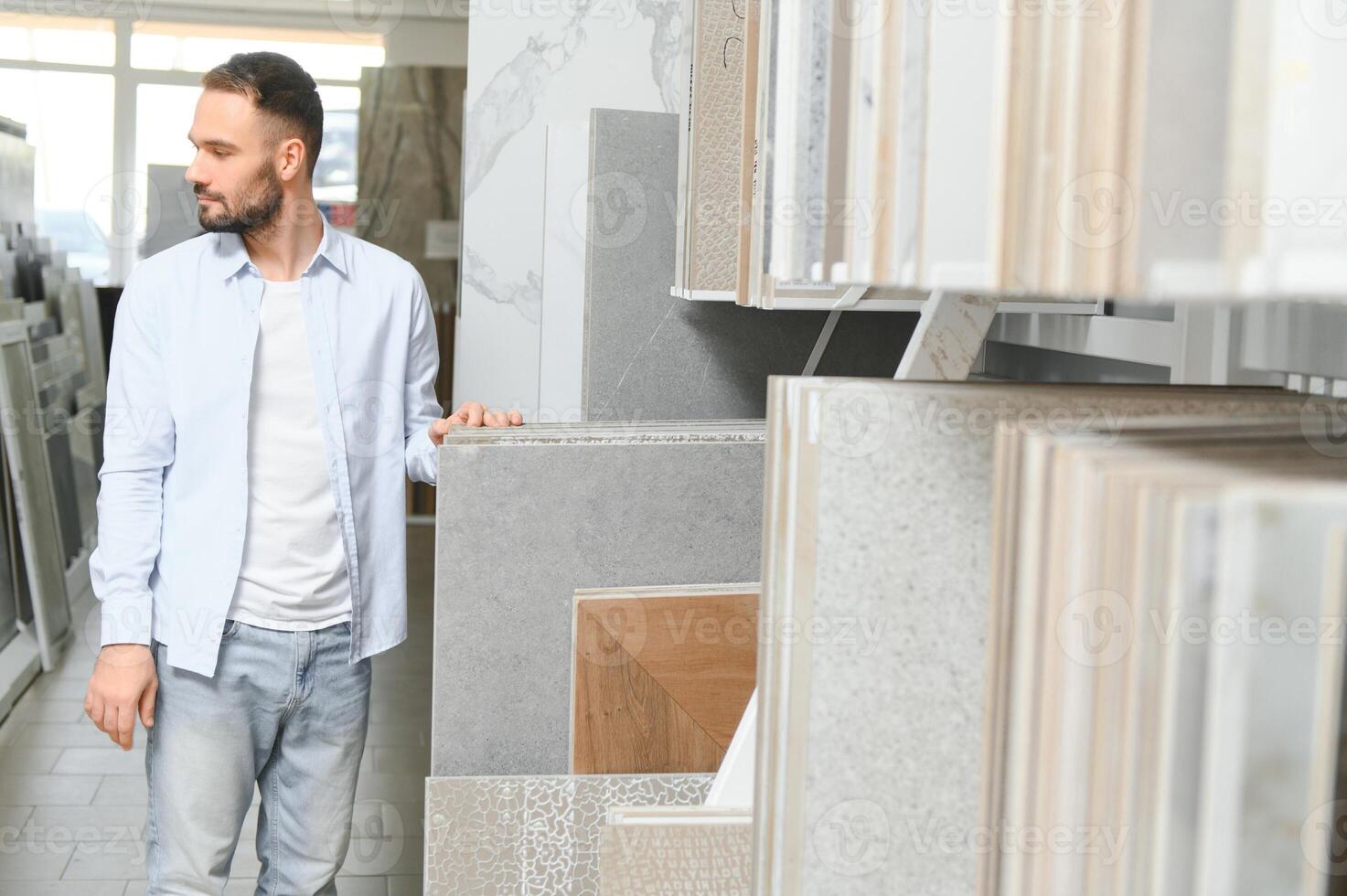 Young man choosing tiles at building market photo