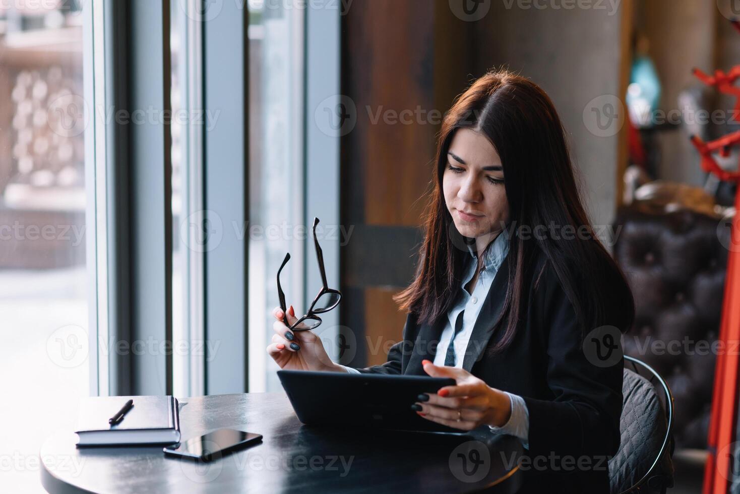 contento joven mujer de negocios utilizando tableta computadora en un cafetería. selectivo atención foto