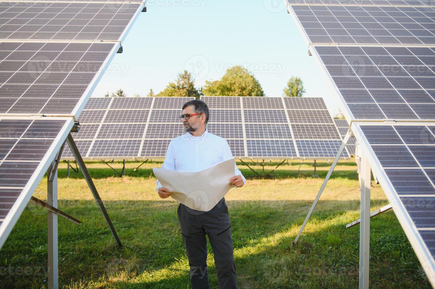 Senior male engineer inspects solar panels on farm. Clean energy. photo