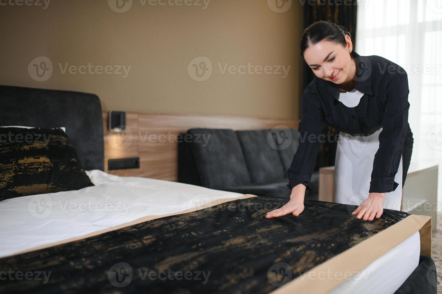 Young hotel maid making the bed photo