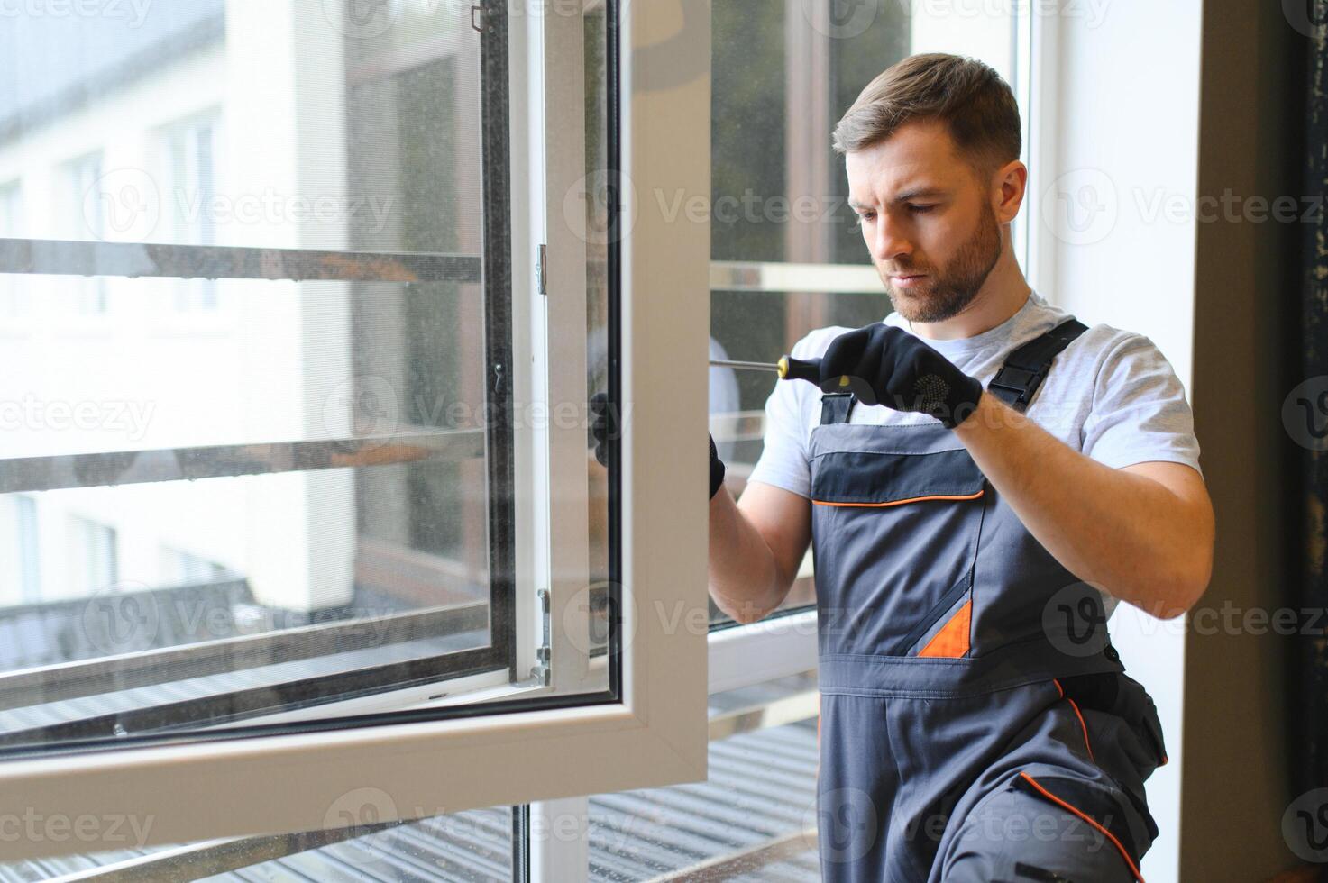 obrero en mono instalando o ajustando el plastico ventanas en el vivo habitación a hogar foto