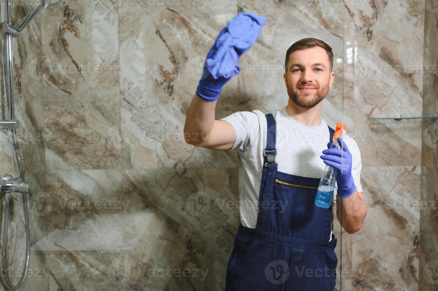 Cleaning service concept. Man cleaning glass cabinet in bathroom photo