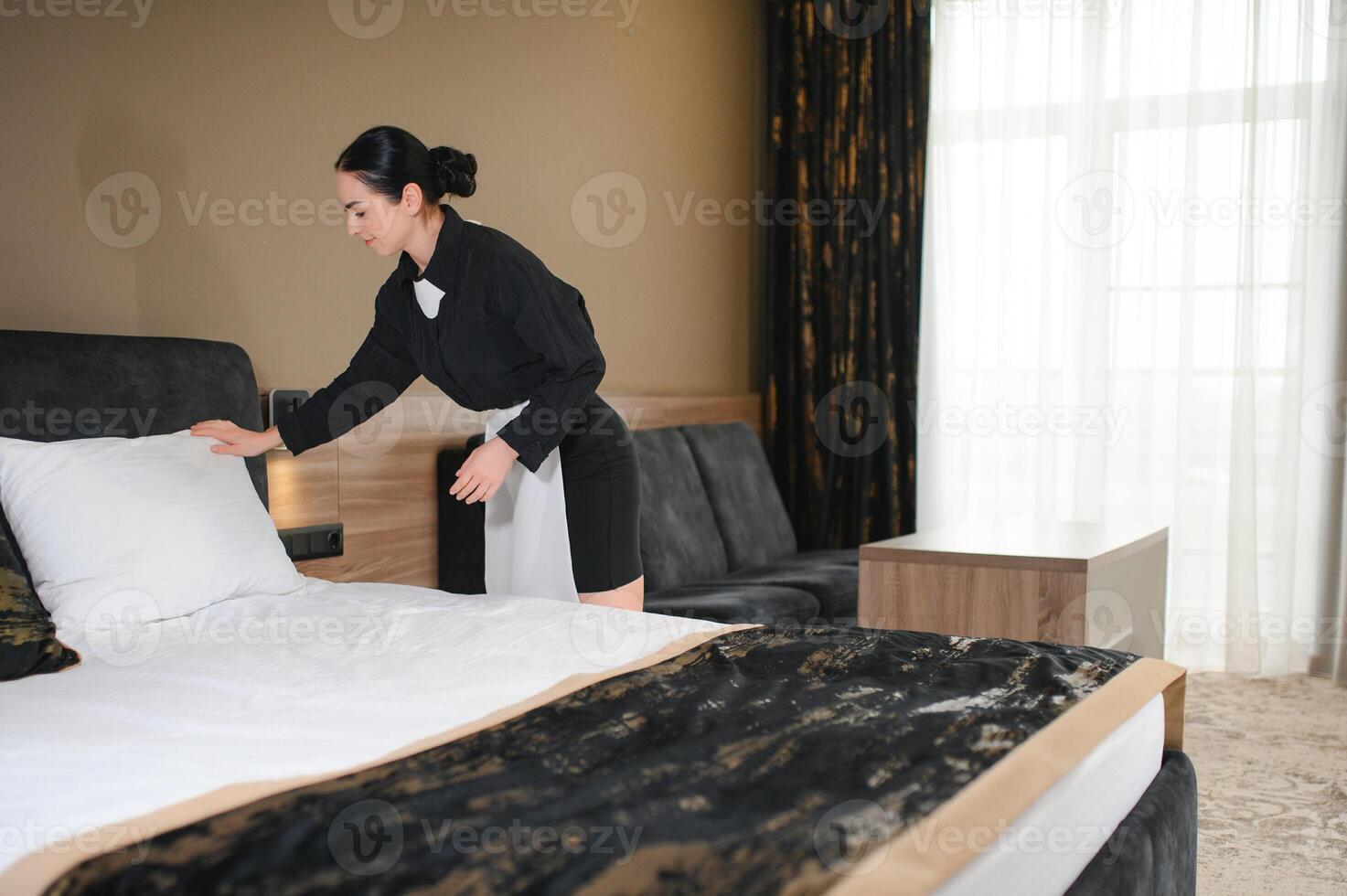 Young hotel maid making the bed photo