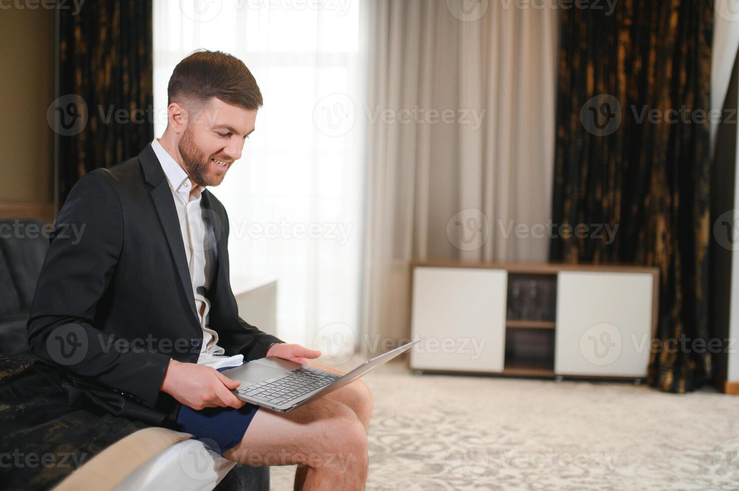 Businessman with no pants working at home. Young man using the laptop having call photo