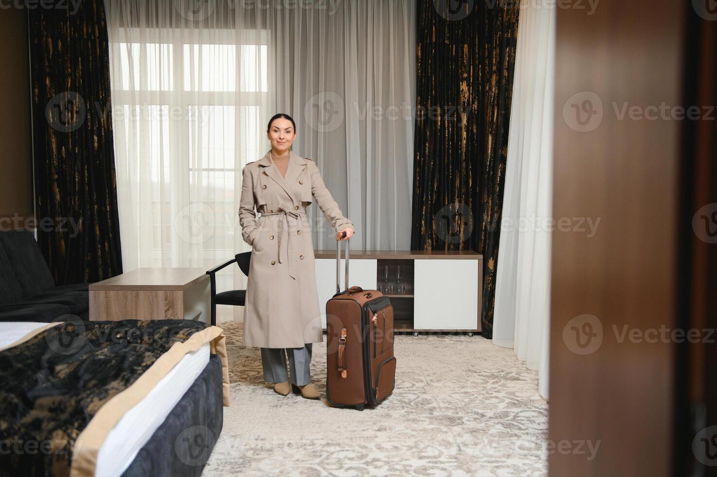 Business woman walking into hotel room with luggage photo