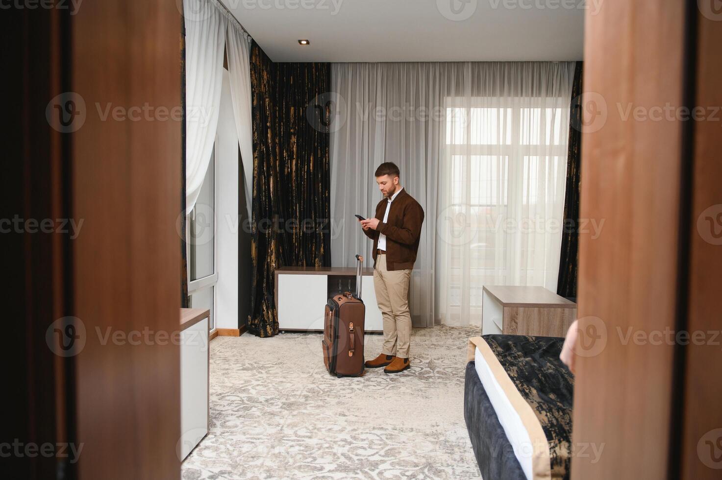 joven empresario con maleta en pie a hotel habitación. negocio viaje concepto foto