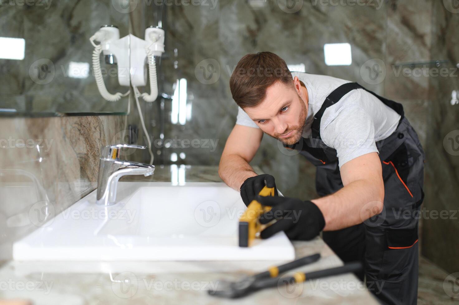 A man is setting the washbasin over the cabinet in the bathroom photo