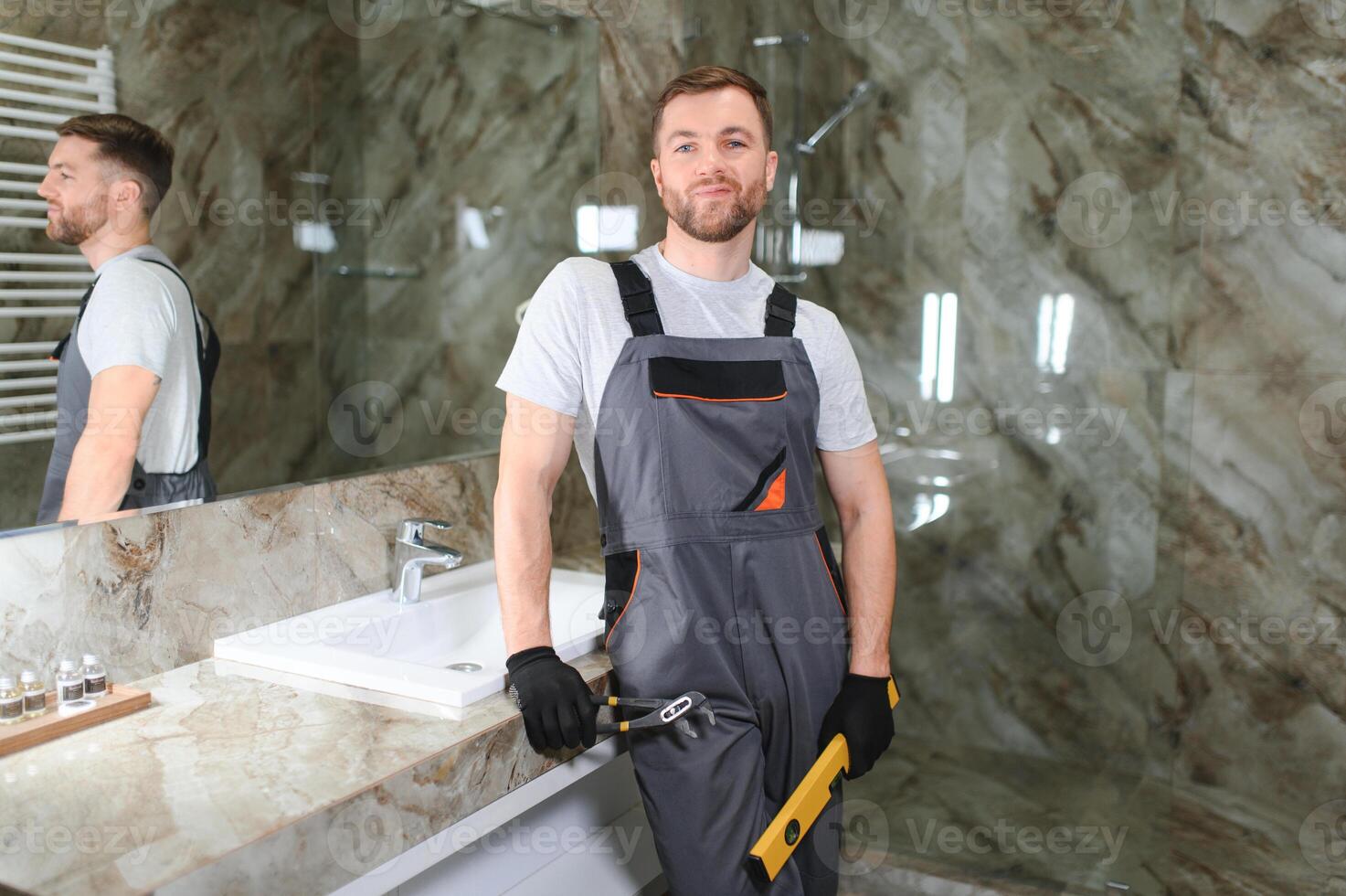 Handsome plumber working in restroom photo