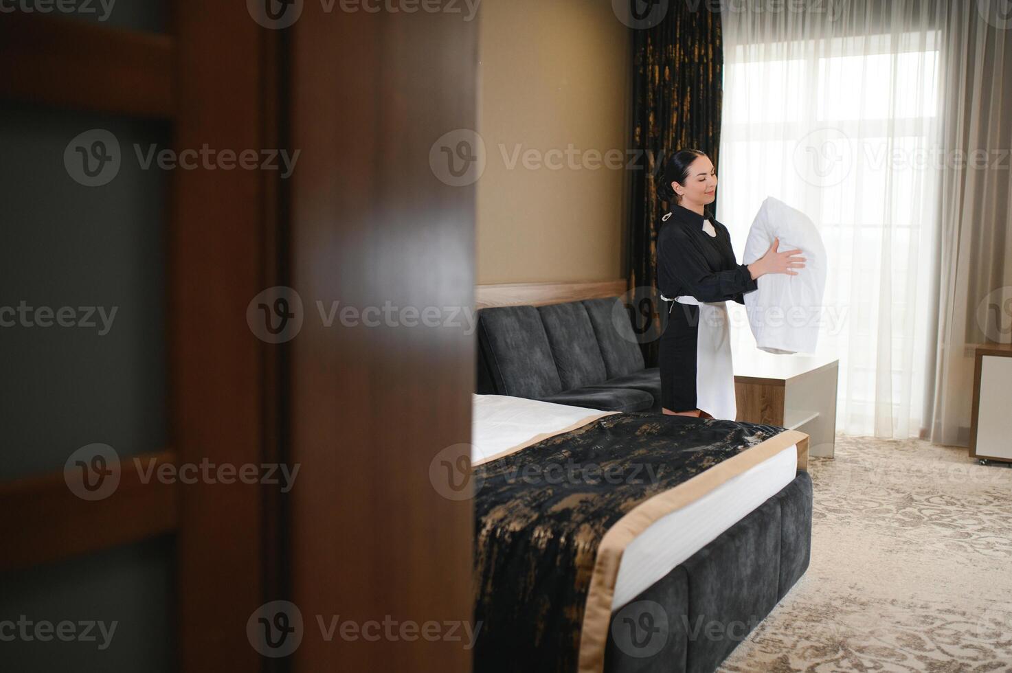 Maid holding fresh towels with flowers in hotel room photo