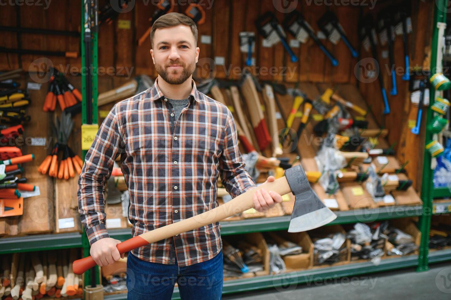 A young man chooses axe in the hardware store photo