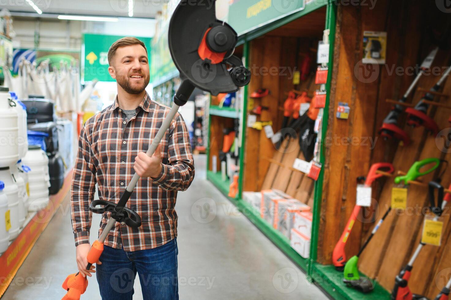 happy customer with electric lawn trimmer in hands at garden equipment store photo