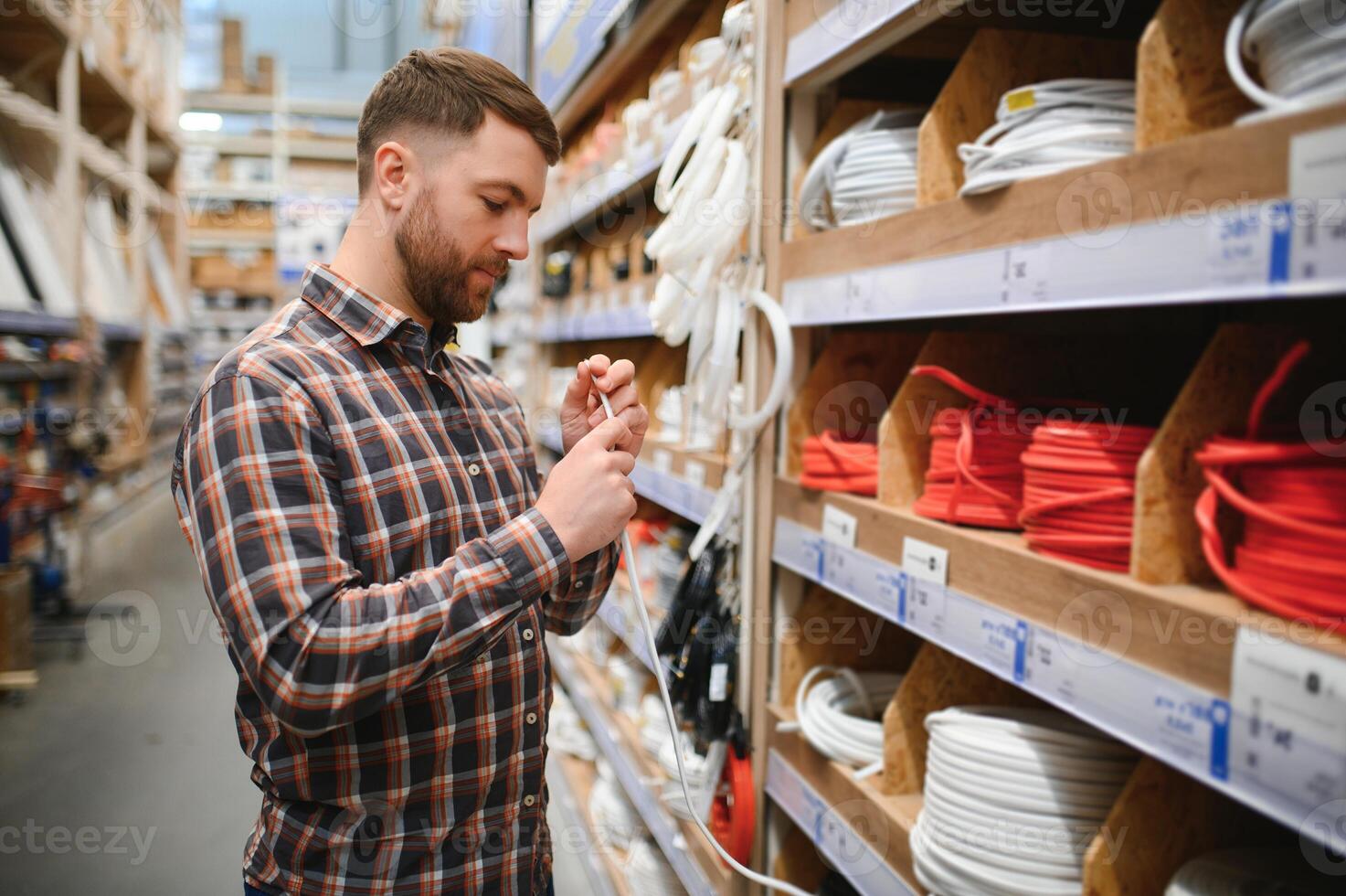 Worker selects an electrical cable at a hardware store photo