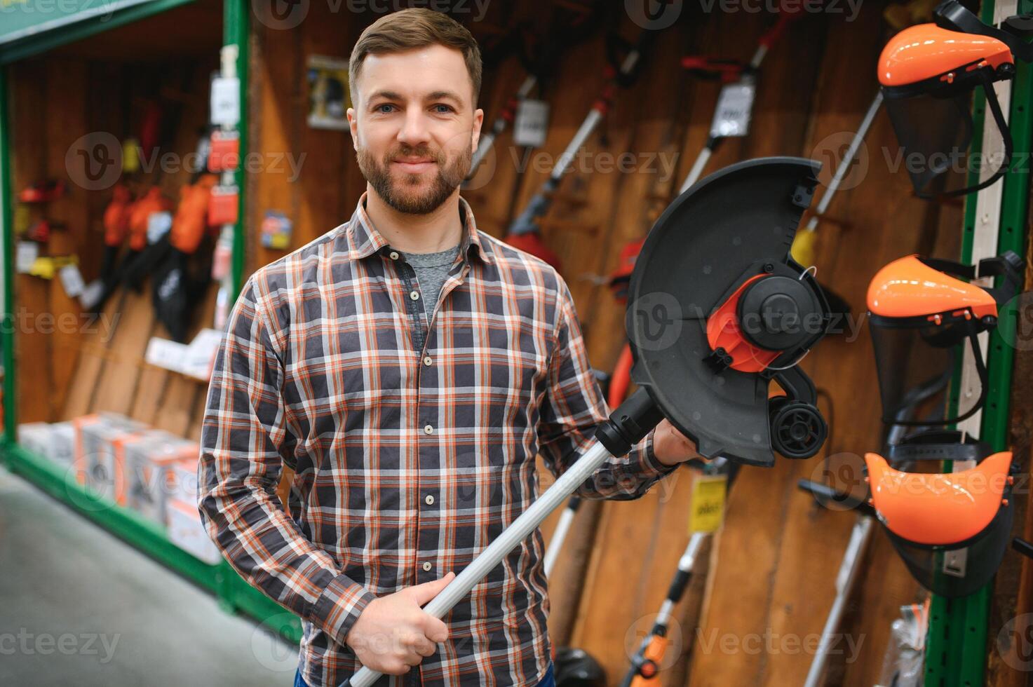 happy customer with electric lawn trimmer in hands at garden equipment store photo