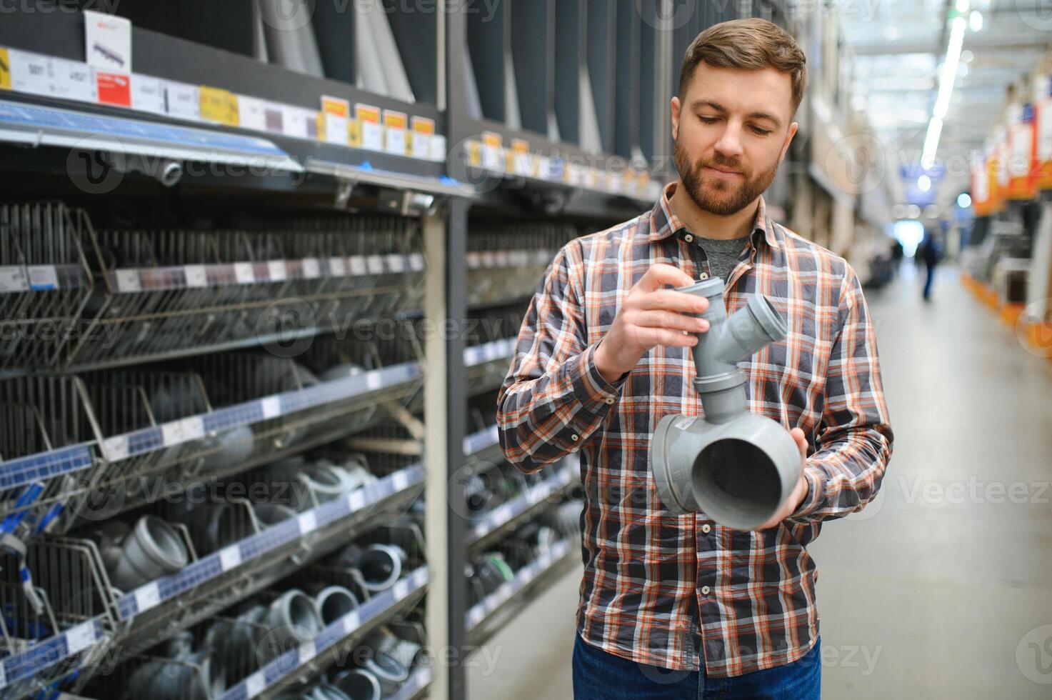 male plumber in a hardware store chooses the sewer pipes, the concept of plumbing work in the house photo