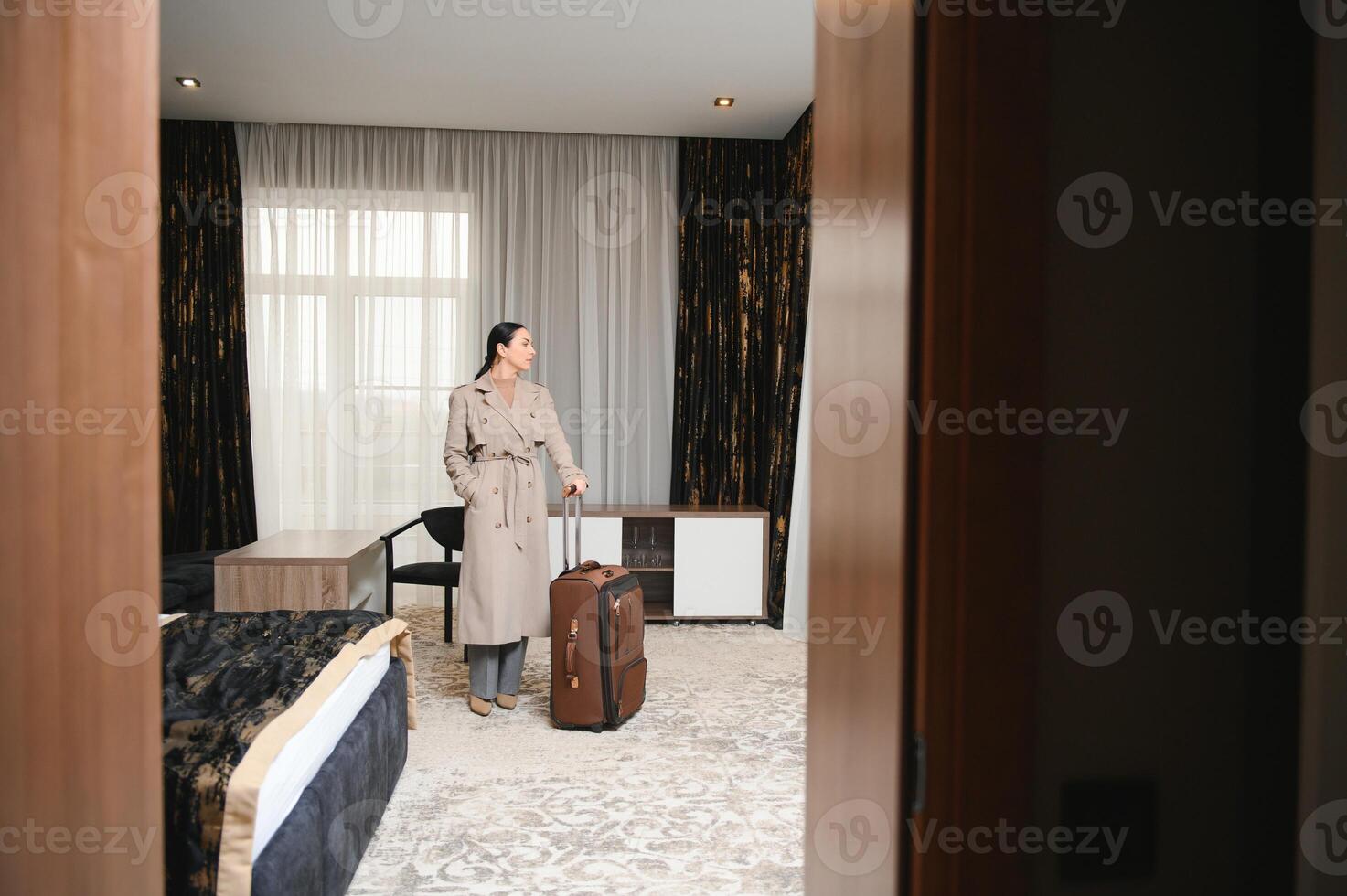 Business woman walking into hotel room with luggage photo