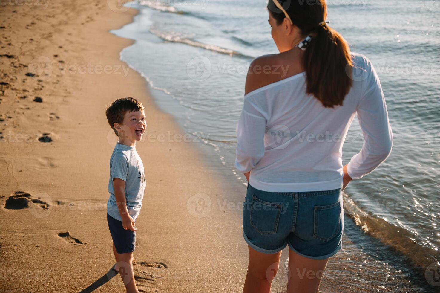 madre y hijo jugando en el playa a el puesta de sol tiempo. concepto de simpático familia foto