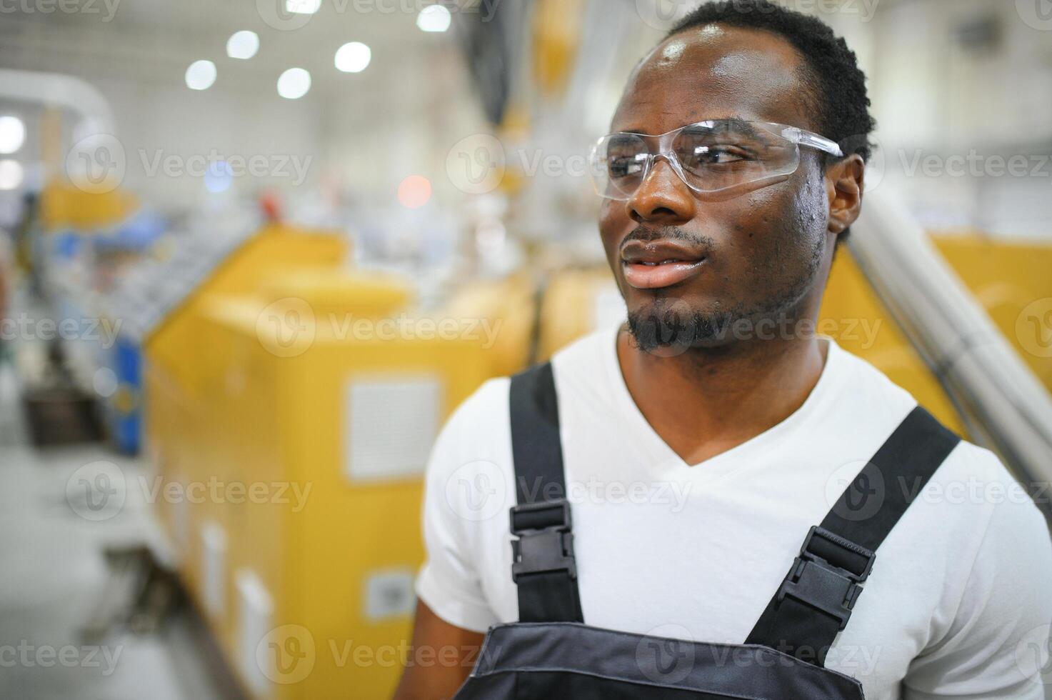 Industrial worker indoors in factory. Young technician with white hard hat photo