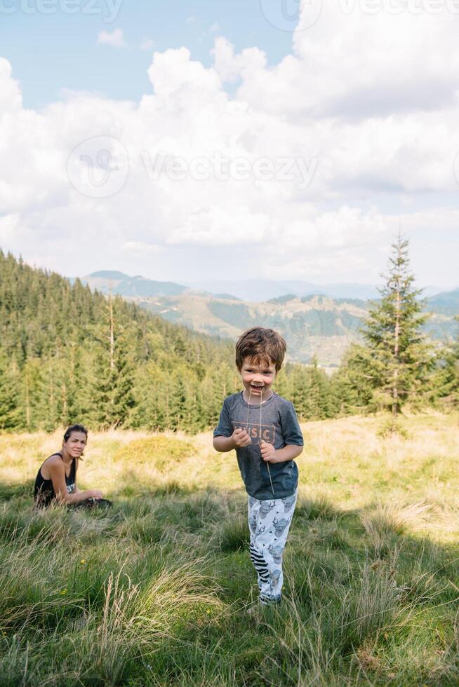 joven mamá con bebé chico de viaje. madre en excursionismo aventuras con niño, familia viaje en montañas. nacional parque. caminata con niños. activo verano vacaciones. ojo de pez lente. foto