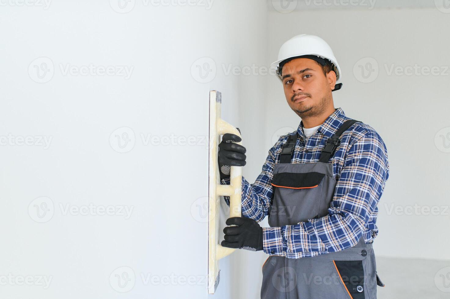 An Indian worker works in an empty apartment. A man in a uniform makes repairs inside the building photo