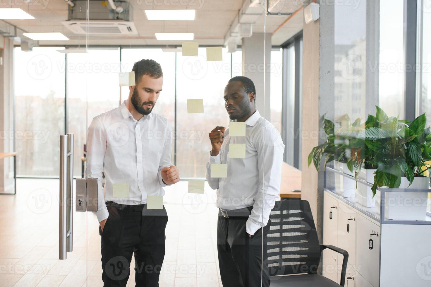 colleagues discuss and stick notes on the glass photo