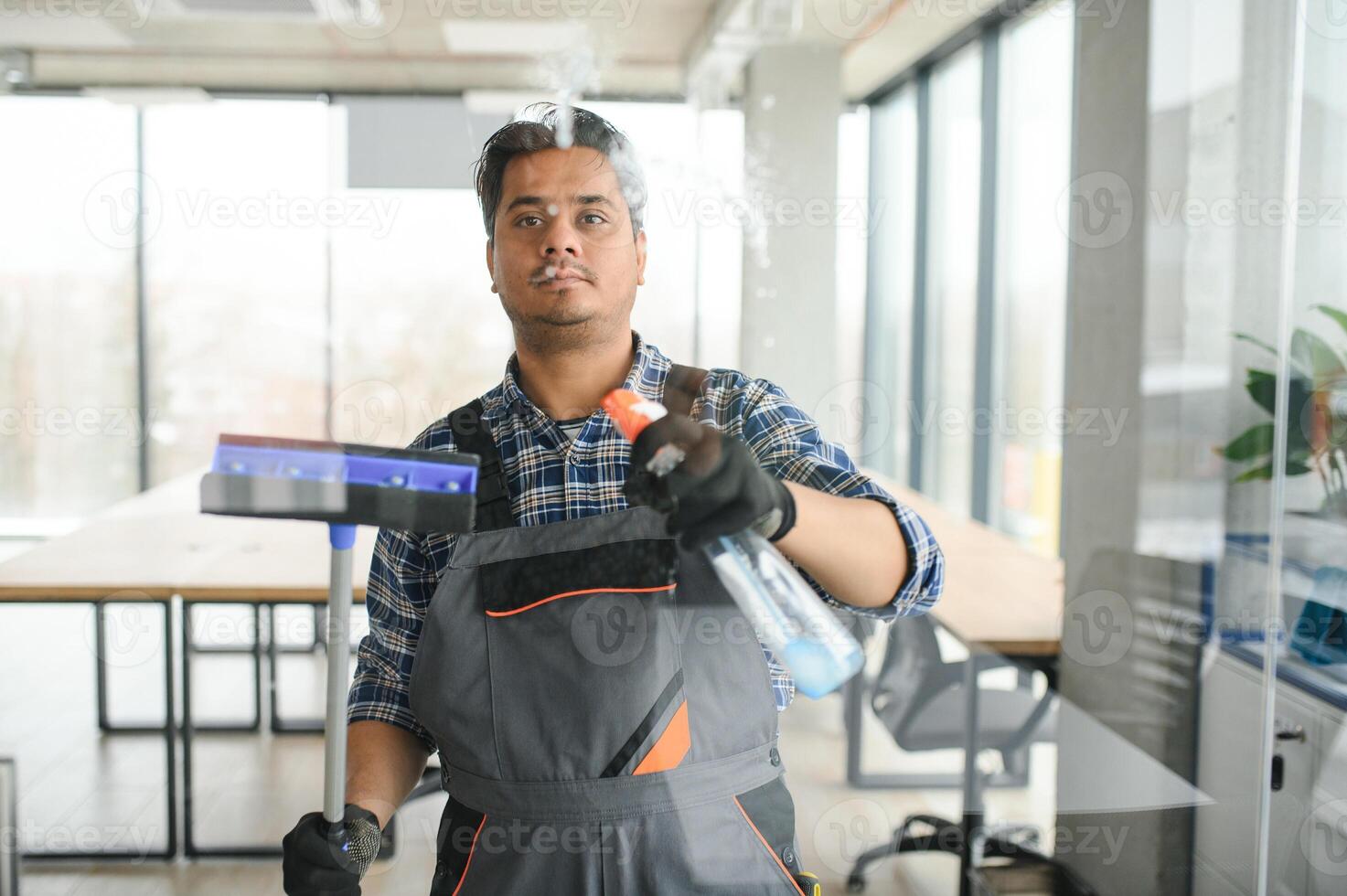 Male janitor cleaning window in office photo