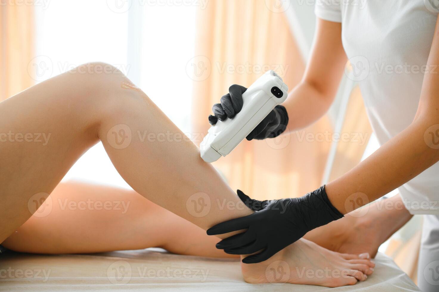 Beautician waxing female legs in spa center photo