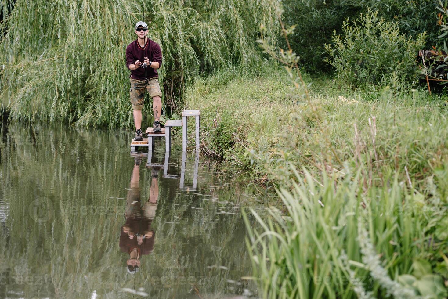 pescador en el verano antecedentes. pescador en su mano participación hilado. pesca, hilado carrete, pez, breg ríos - el concepto de un rural escapar. artículo acerca de pescar foto