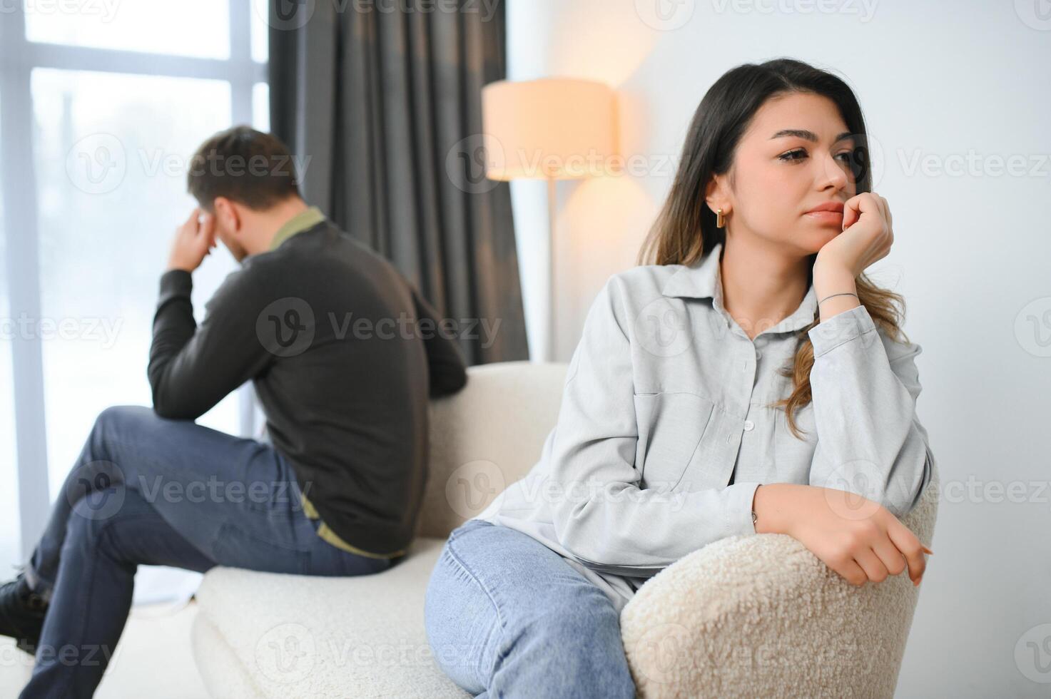 Beautiful couple is sitting back to back on the couch while having a quarrel photo