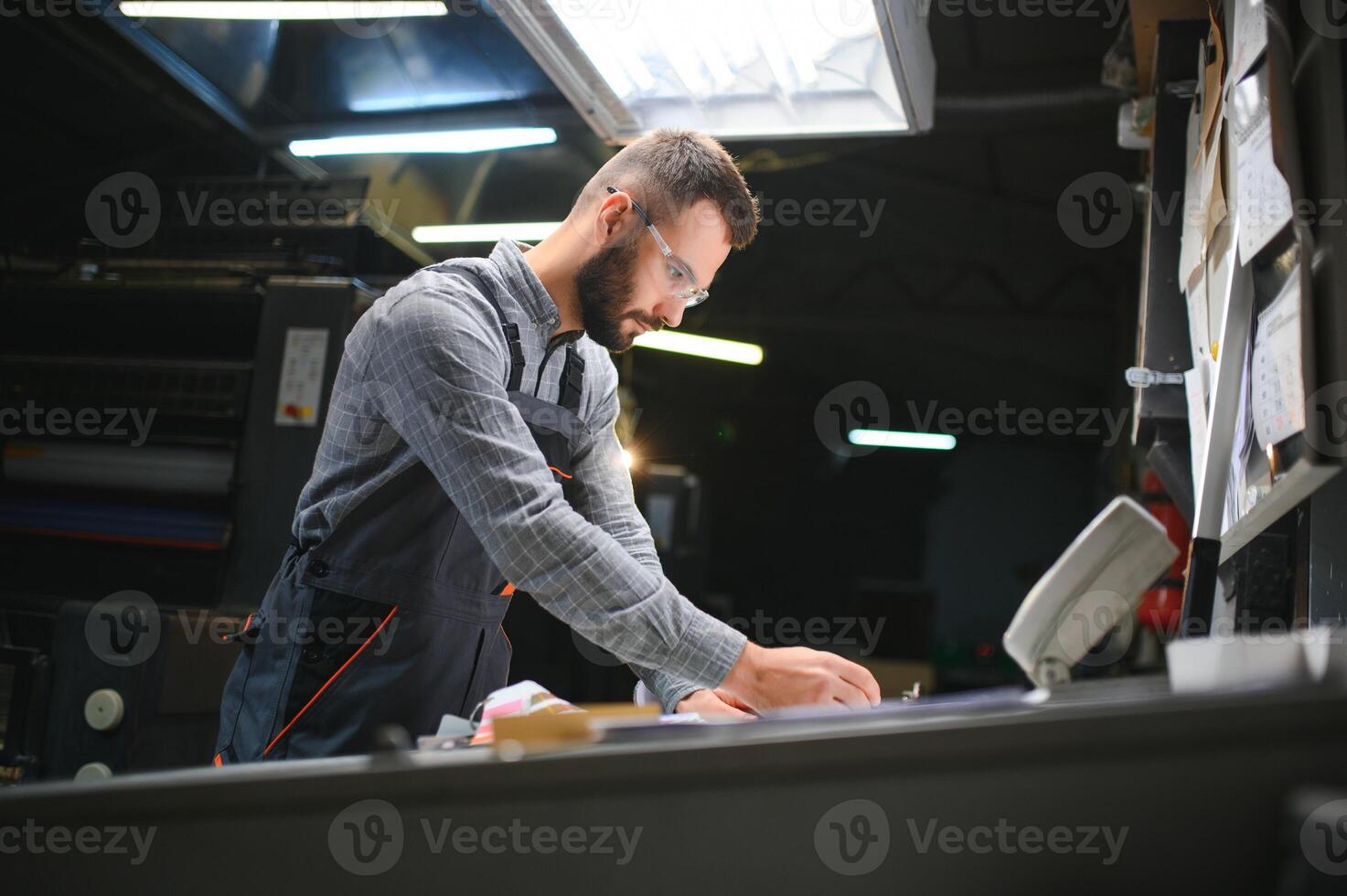 Man working in printing house with paper and paints photo