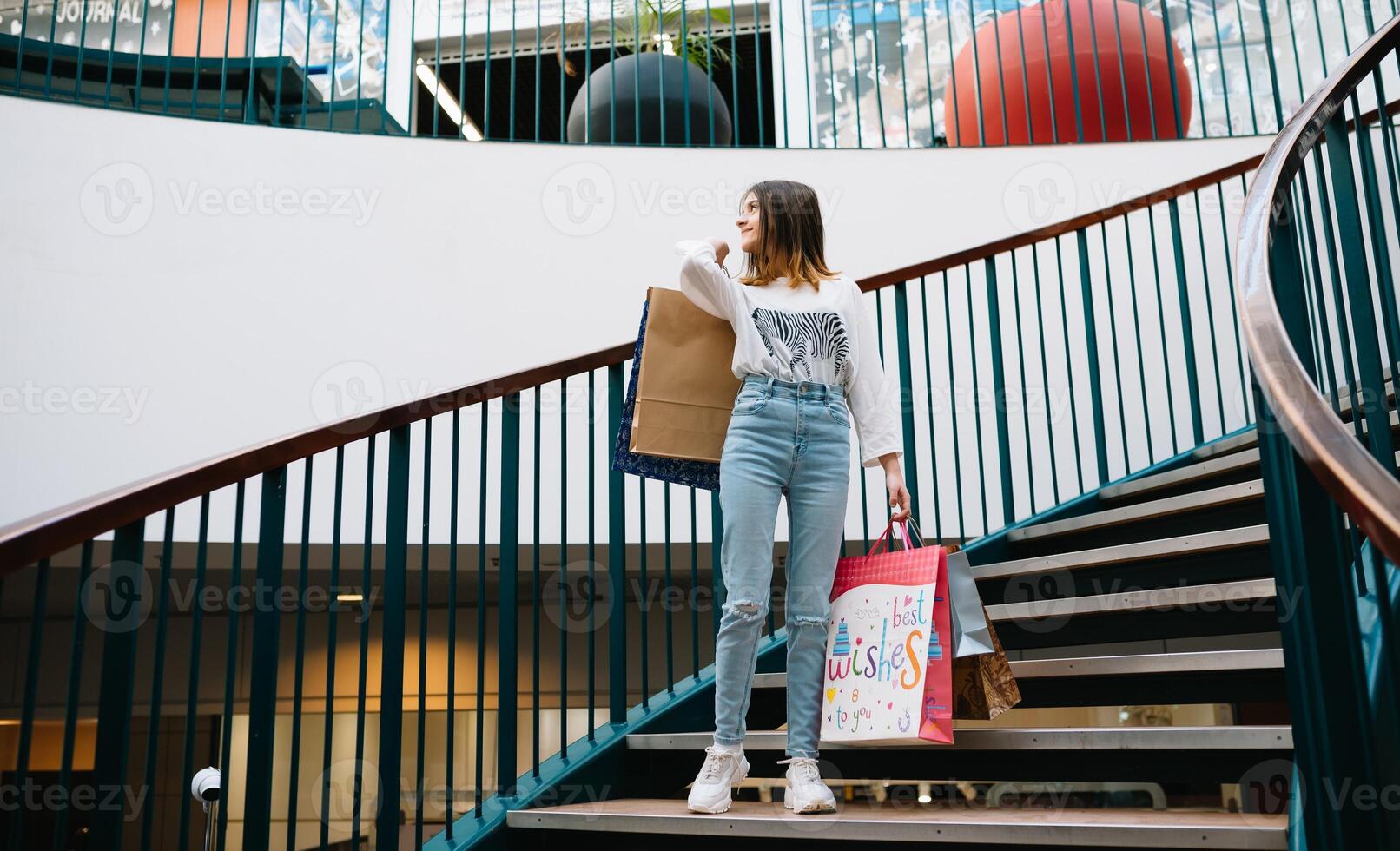 retail, gesture and sale concept - smiling teenage girl with many shopping bags at mall. shopping concept photo